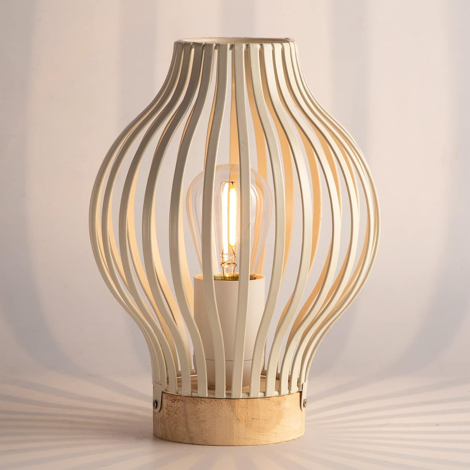 Hecha de metal blanco de alta calidad, esta lámpara de mesa portátil con zócalo de madera crea un efecto único de luz y sombra. Funciona con 3 pilas AAA, ideal para usar en cualquier rincón de tu hoga